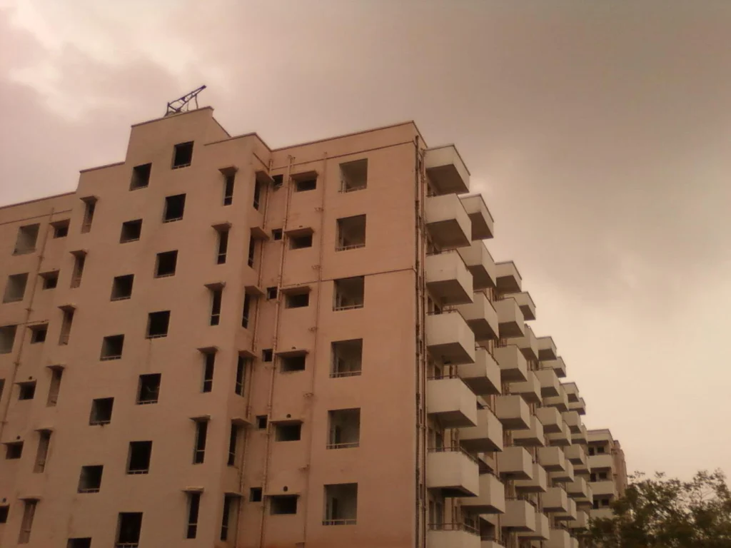 Monsoon clouds over a multi-storey residential building of the kind found across Pune and PCMC